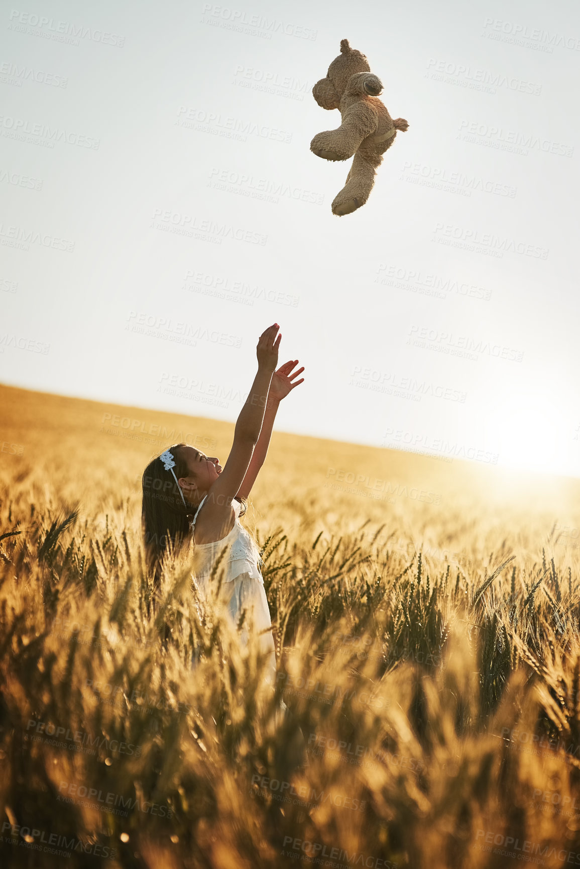 Buy stock photo Shot of a cute little girl playing with her teddybear in a cornfield