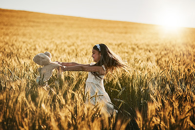 Buy stock photo Shot of a cute little girl playing with her teddybear in a cornfield