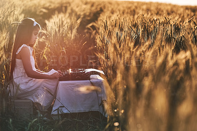 Buy stock photo Outdoor, typing and girl with typewriter, nature and creative in cornfield, writer and child with talent. Morning, kid and relax with ideas for short story in Nebraska, growth or development of youth