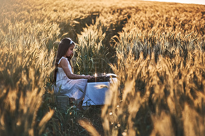 Buy stock photo Outdoor, writer and girl with typewriter, nature and creative in cornfield, typing and child with talent. Morning, kid and relax with ideas for short story in Nebraska, growth or development of youth