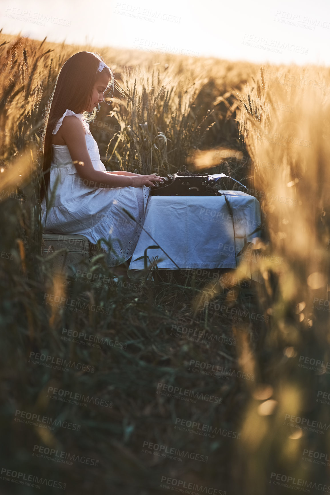 Buy stock photo Outdoor, countryside and girl with typewriter, nature and creative in cornfield, typing and child with talent. Morning, kid and relax with ideas for short story in Nebraska, growth and development