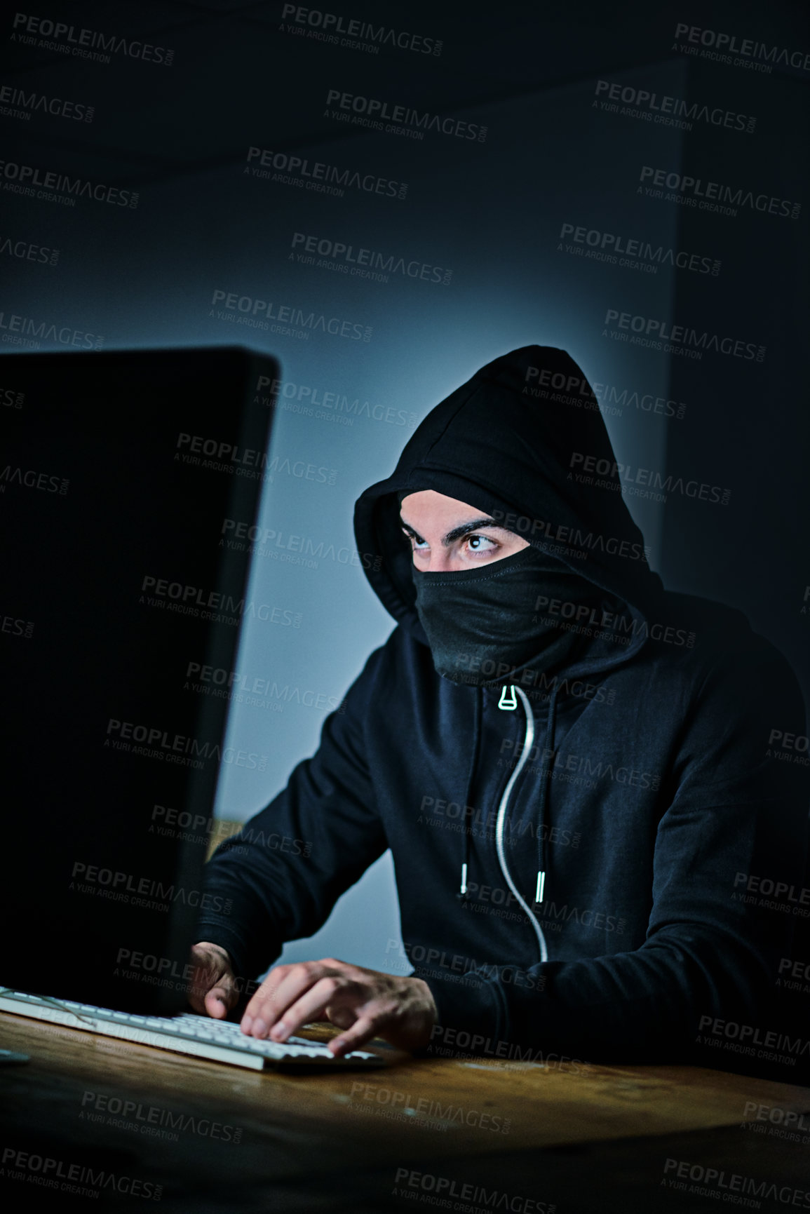 Buy stock photo Shot of a young hacker using a computer late at night