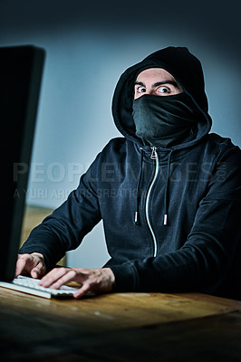 Buy stock photo Portrait of a young hacker using a computer late at night