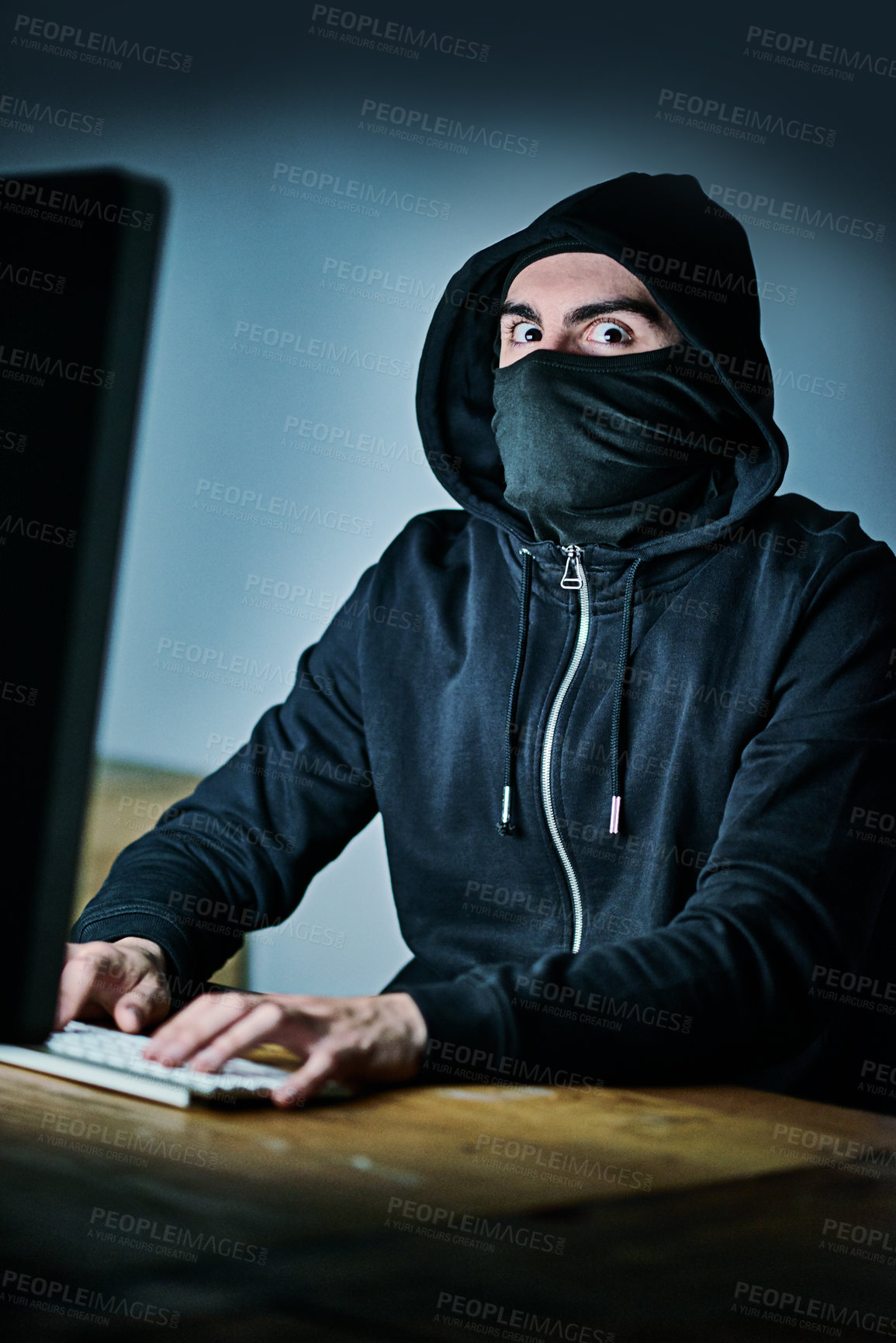 Buy stock photo Portrait of a young hacker using a computer late at night