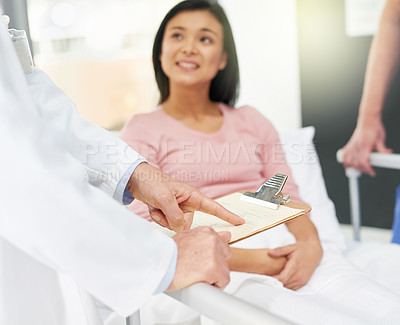 Buy stock photo Shot of a young patient looking up at her unidentifiable doctor during a consultation