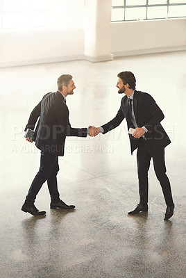 Buy stock photo High angle shot of two businessmen shaking hands in an office lobby