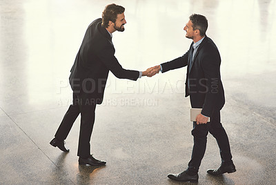 Buy stock photo High angle shot of two businessmen shaking hands in an office lobby