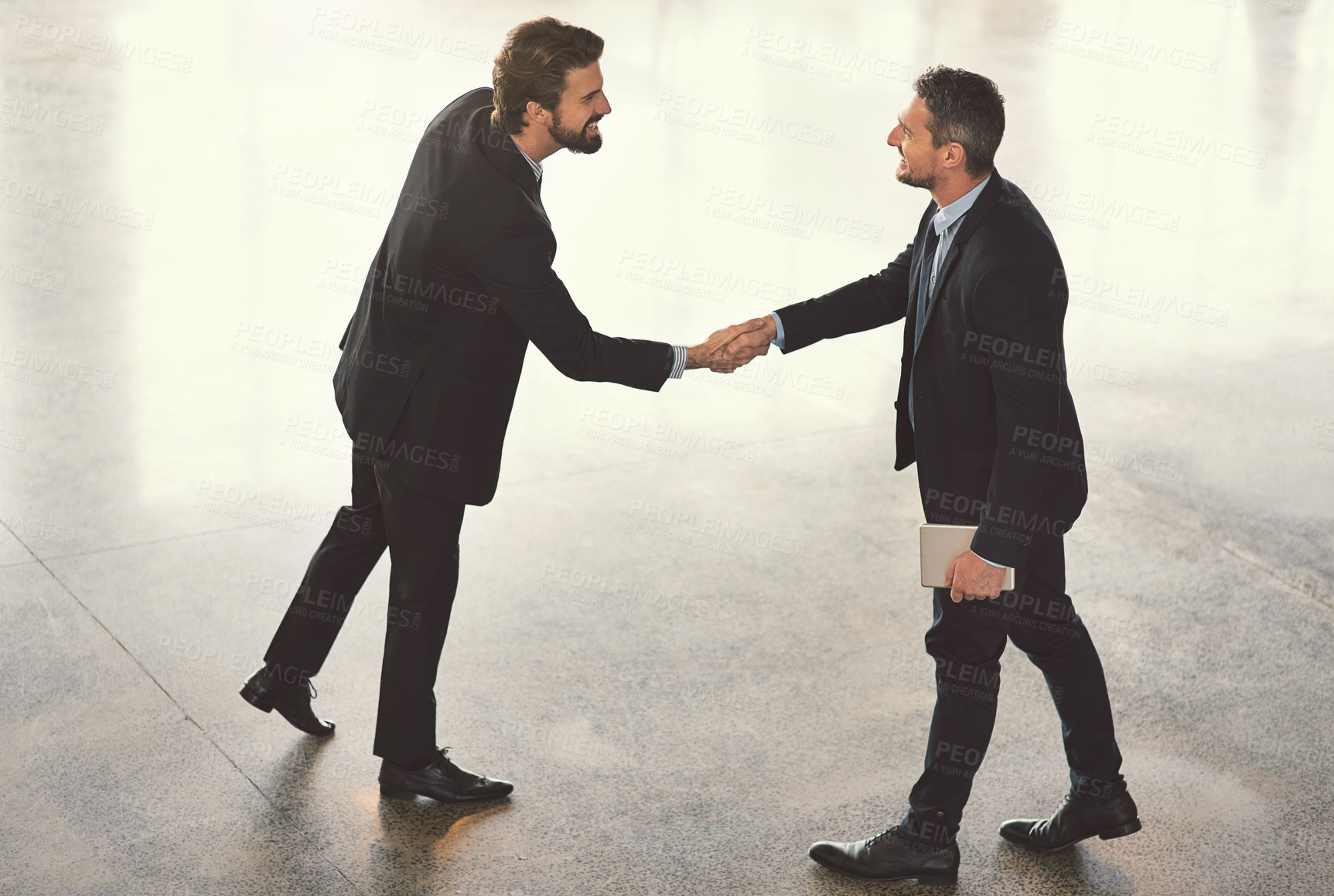 Buy stock photo High angle shot of two businessmen shaking hands in an office lobby