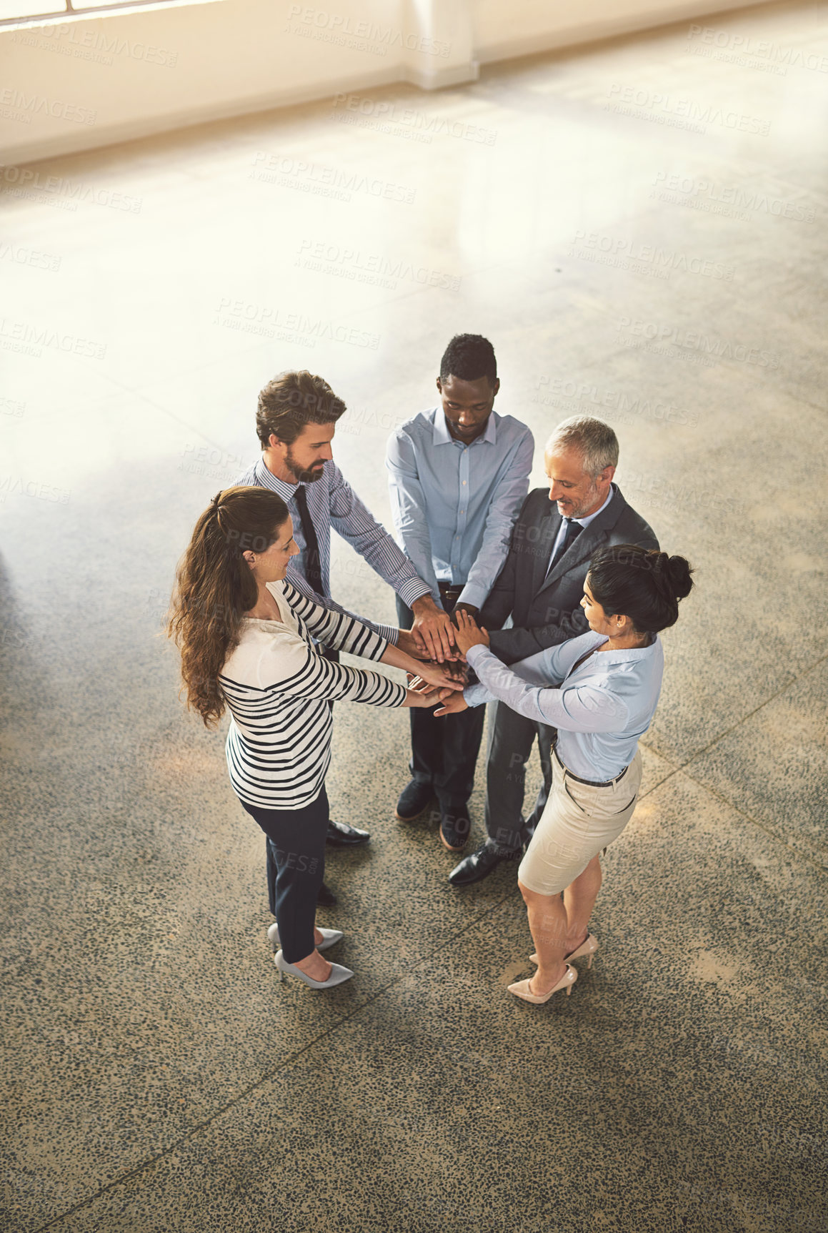 Buy stock photo High angle shot of a group of businesspeople standing in a huddle together in an office lobby