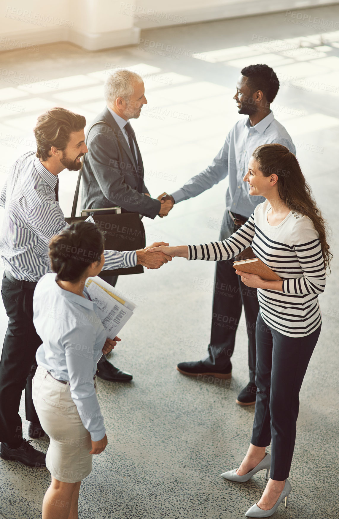 Buy stock photo High angle shot of businesspeople shaking hands while standing in an office lobby