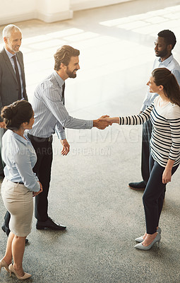 Buy stock photo High angle shot of businesspeople shaking hands while standing in an office lobby
