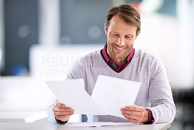 Buy stock photo Shot of a mature businessman reading paperwork while sitting in an office