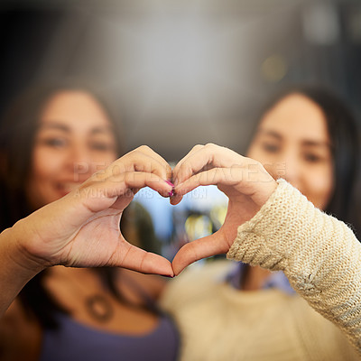 Buy stock photo Portrait of two young friends making a heart shape with their hands