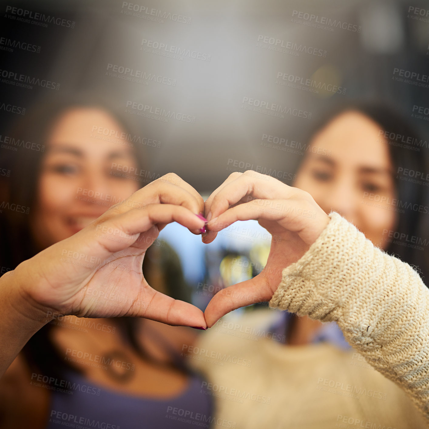 Buy stock photo Portrait of two young friends making a heart shape with their hands