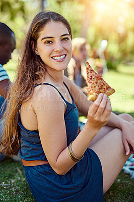 Buy stock photo Portrait of a young woman eating pizza while out on a picnic with friends