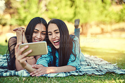 Buy stock photo Cropped shot of two young friends taking a selfie together at the park