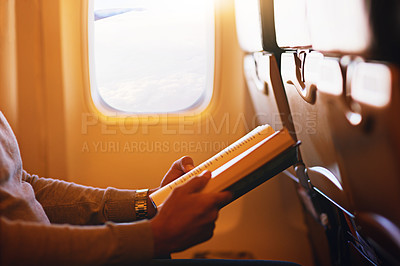 Buy stock photo Shot of a passenger reading a book on an airplane