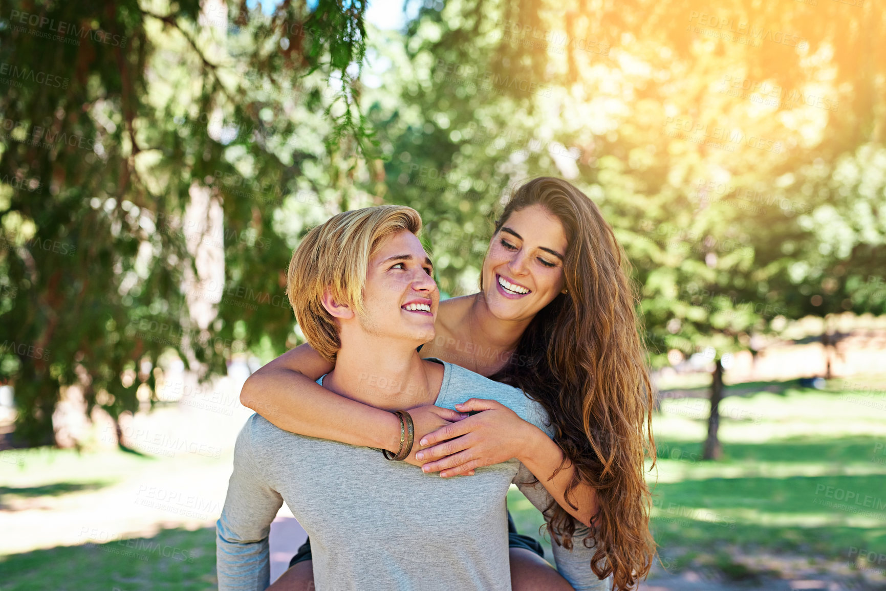 Buy stock photo Shot of a happy young couple enjoying a piggyback ride outdoors