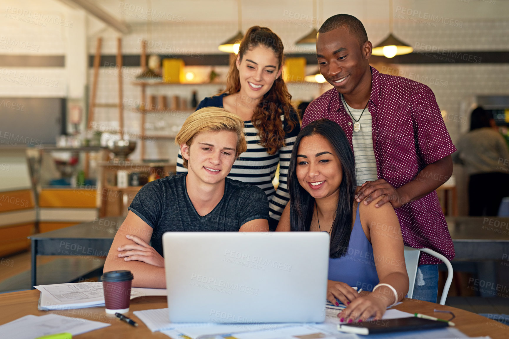 Buy stock photo Shot of a group of young friends using a laptop while studying in a cafe