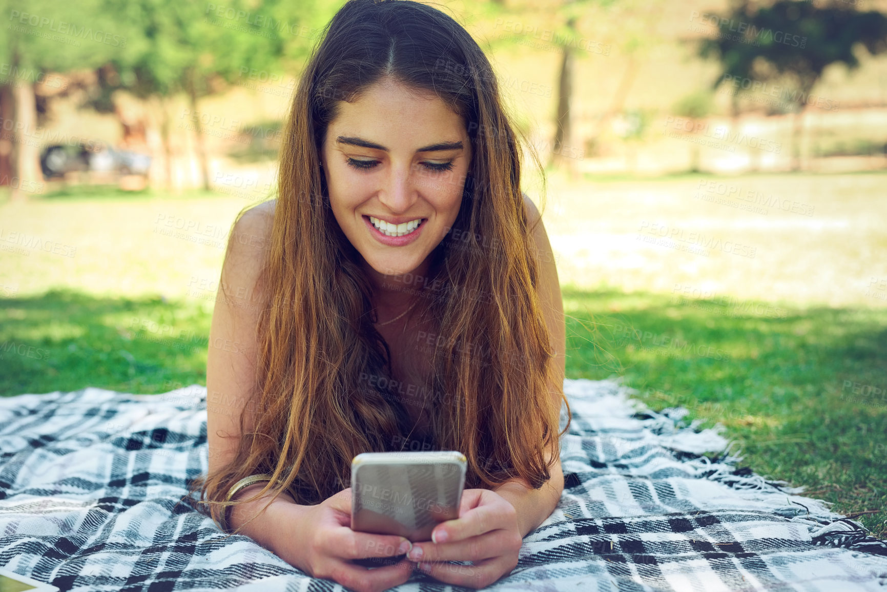 Buy stock photo Blanket, phone and picnic with woman at park in summer for communication, networking or social media. App, face and smile with happy person outdoor on grass with mobile for browsing or text message