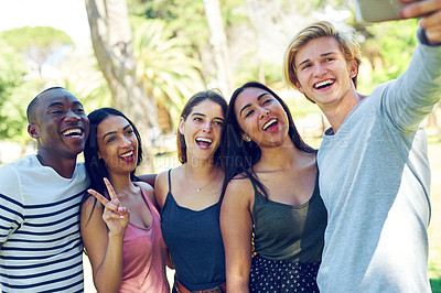 Buy stock photo Shot of a group of young friends taking a selfie together outdoors