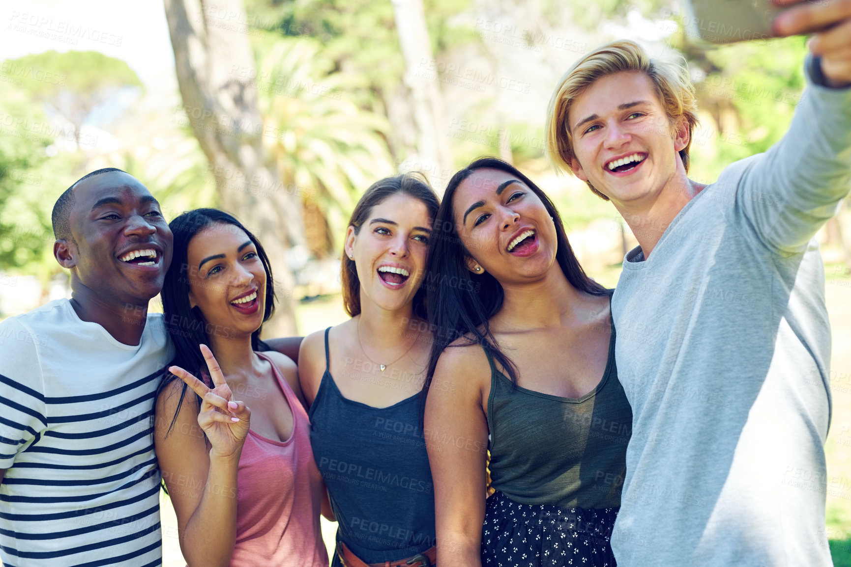 Buy stock photo Shot of a group of young friends taking a selfie together outdoors