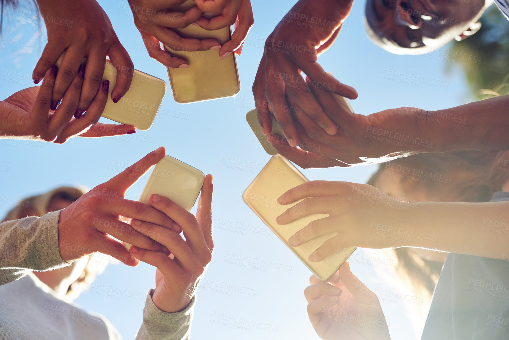 Buy stock photo Hands, low angle and phone by friends together for social media, networking and sharing app on blue sky background. Below, smartphone and gen z people with internet, addiction or online communication