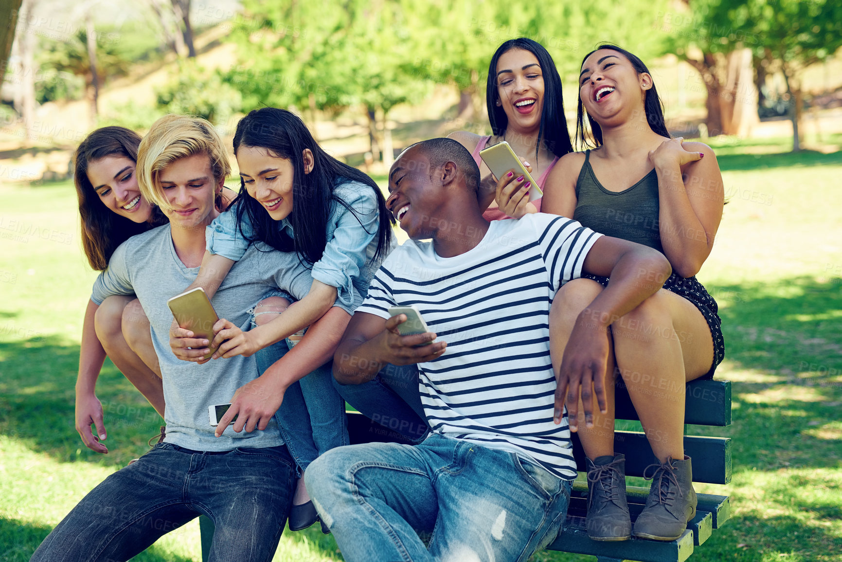 Buy stock photo Group, people and phone with laugh on park bench at college with meme, video or watch live stream on app. Men, women and students for diversity, funny post and relax with friends with social media