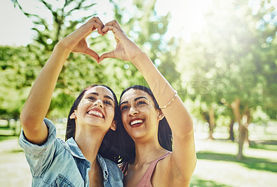 Buy stock photo Shot of two happy young friends joining their hands to make a heart shape