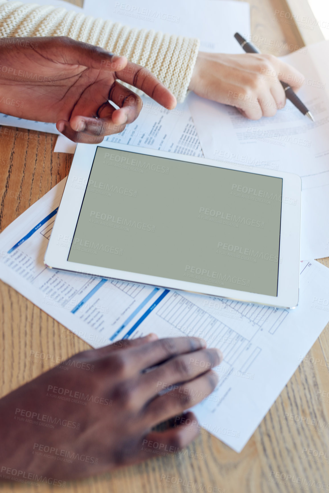 Buy stock photo Shot of two unidentifiable team members using a tablet while working together at a table