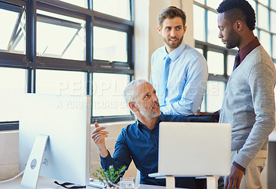 Buy stock photo Shot of a group of businesspeople working together at a computer in the office