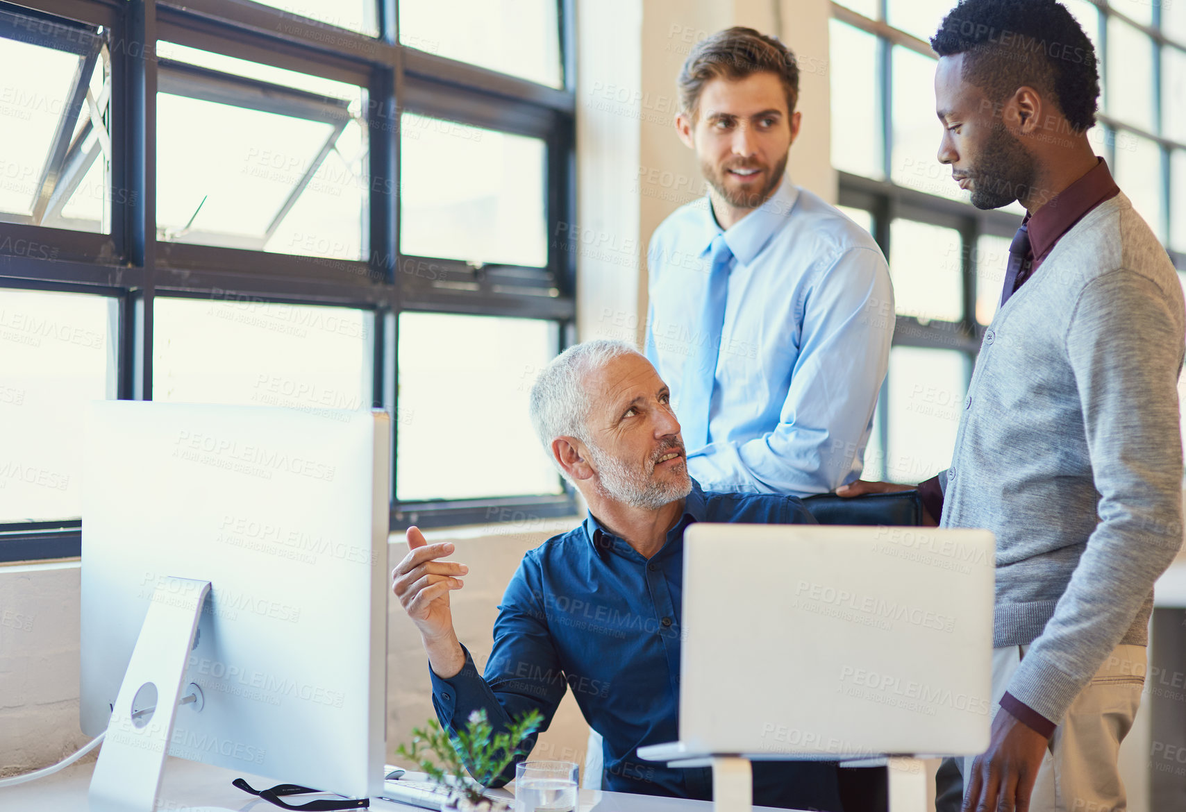 Buy stock photo Shot of a group of businesspeople working together at a computer in the office