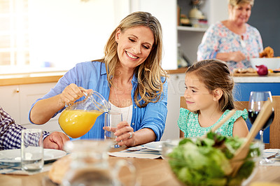 Buy stock photo Shot of a mother pouring juice into a glass for her little daughter at home
