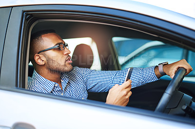 Buy stock photo Cropped shot of a young businessman using a cellphone while driving a car