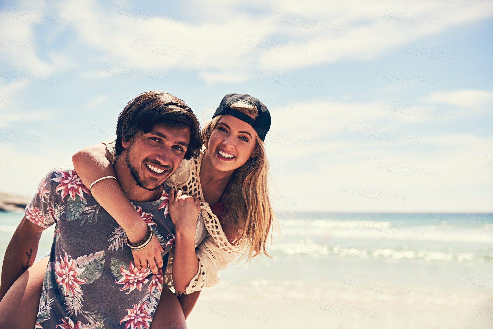 Buy stock photo Portrait of an attractive young woman getting a piggyback from her boyfriend on the beach