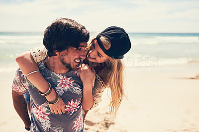 Buy stock photo Shot of an attractive young woman getting a piggyback from her boyfriend on the beach