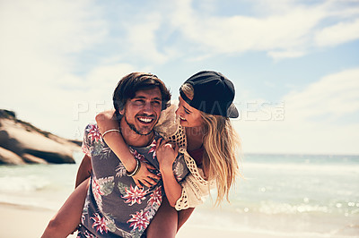 Buy stock photo Shot of an attractive young woman getting a piggyback from her boyfriend on the beach