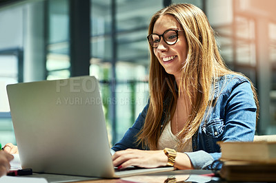 Buy stock photo Shot of a smiling female university student working on a laptop on campus
