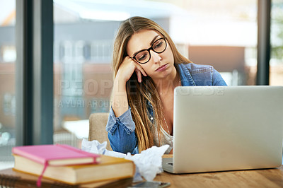 Buy stock photo Shot of a female university student looking bored while sitting at a table on campus using a laptop