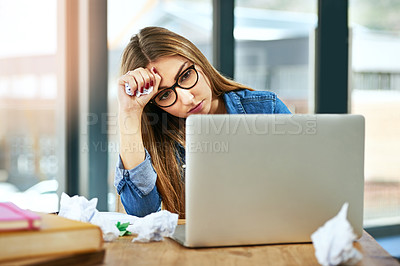 Buy stock photo Shot of a female university student looking stressed while sitting at a table on campus using a laptop