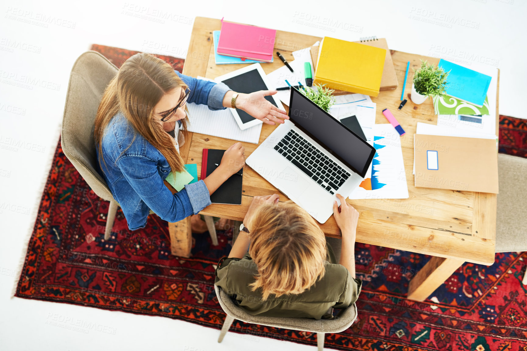 Buy stock photo High angle shot of two female university students working on a project together at a table on campus