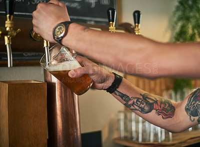 Buy stock photo Cropped shot of an unidentifiable young bartender pouring beer from a tap behind the bar
