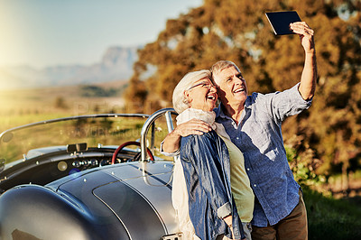 Buy stock photo Shot of a senior couple posing for a selfie while out on a roadtrip in a convertible