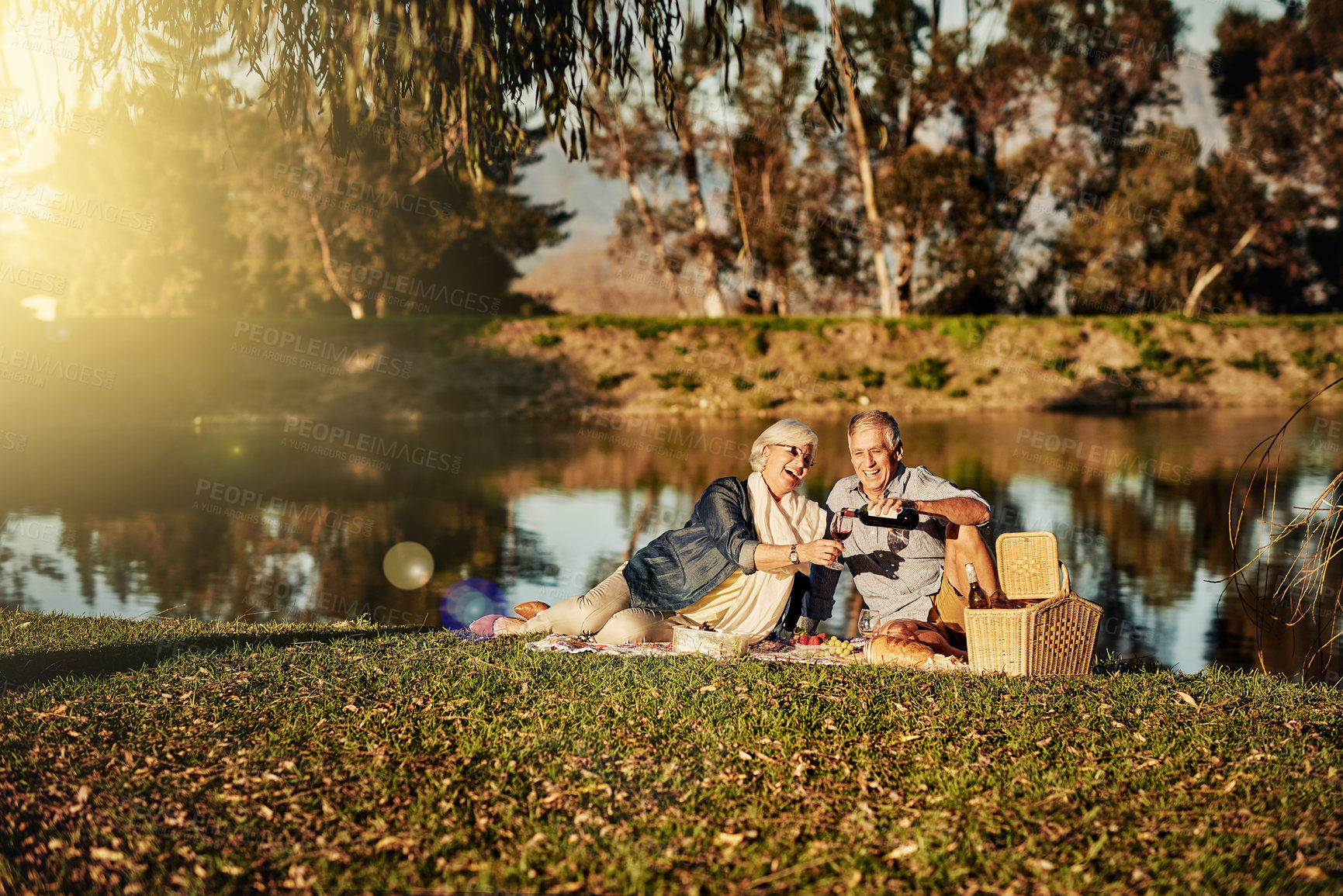 Buy stock photo Senior couple, wine and picnic in outdoor for love, romance and relax by lake in nature. Elderly people, marriage and drink alcohol on vacation, holiday and calm retirement for bonding by river