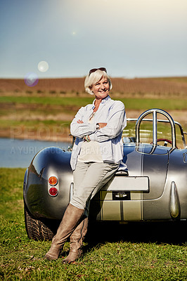 Buy stock photo Shot of a senior woman posing next to a convertible while out on a roadtrip