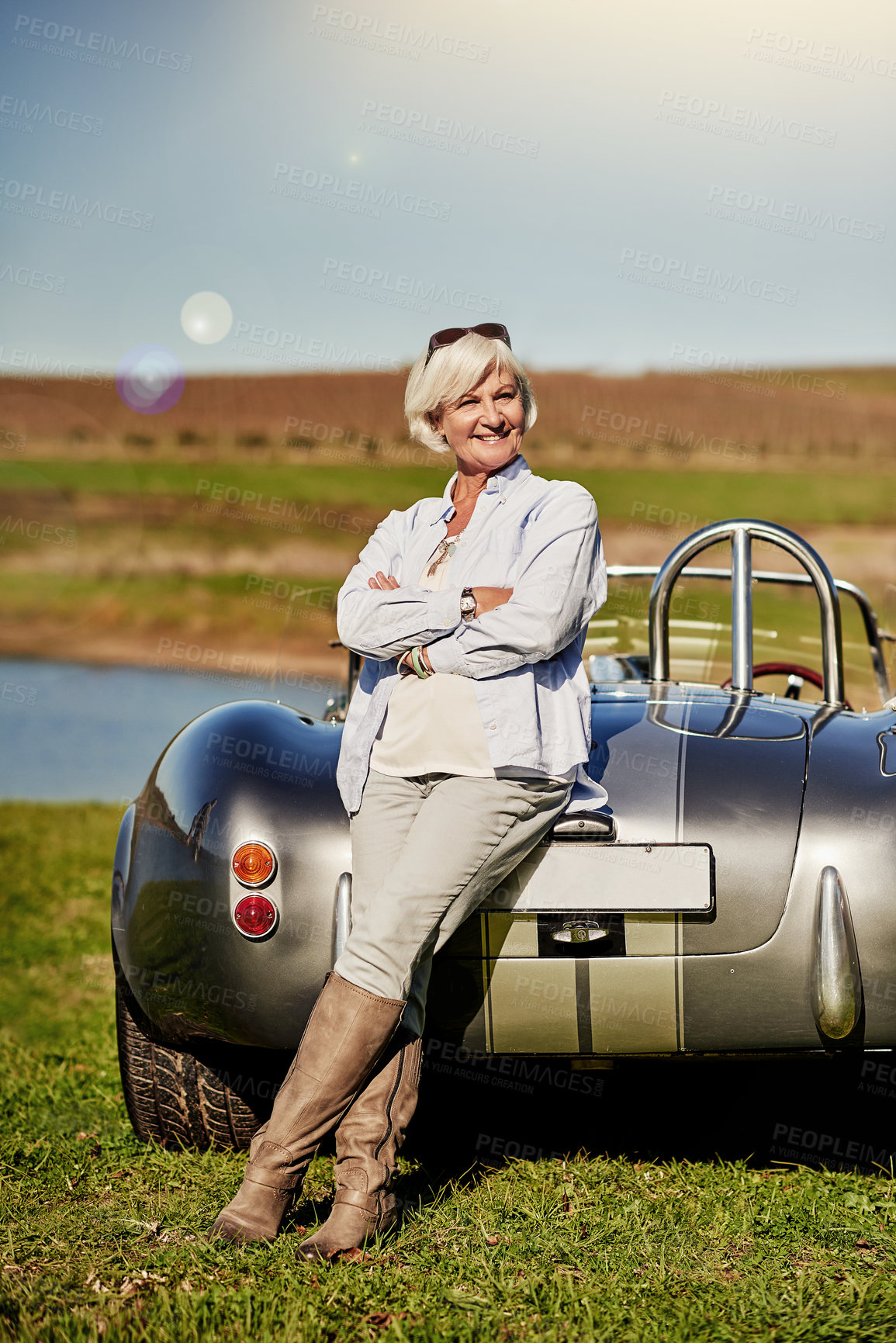Buy stock photo Shot of a senior woman posing next to a convertible while out on a roadtrip