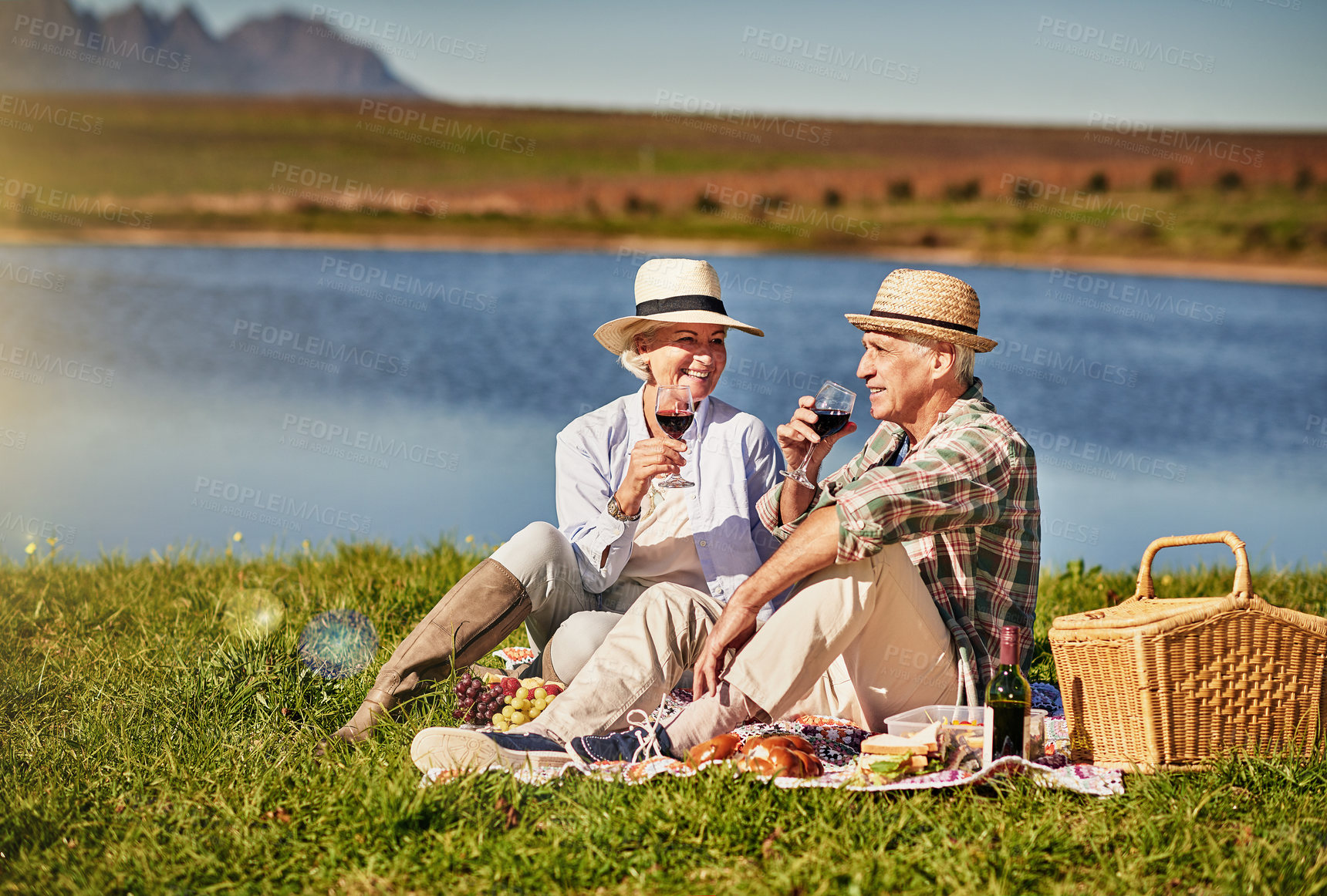 Buy stock photo Senior couple, wine glasses and picnic in outdoor for love, romance and relax by lake in nature. Elderly people, grass and drink alcohol on vacation, holiday and calm retirement for bonding by river