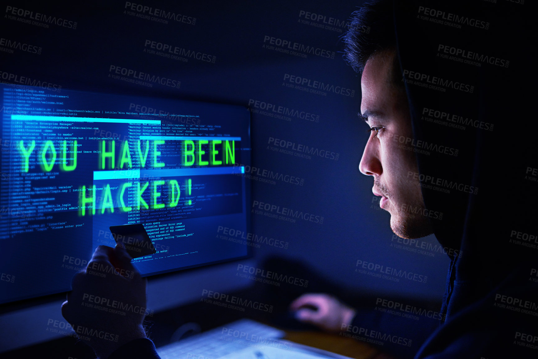 Buy stock photo Shot of a hooded computer hacker using a computer in the dark