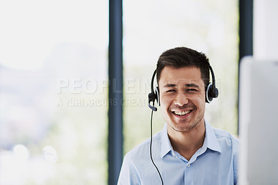 Buy stock photo Portrait of a happy young man wearing a headset and using a computer at work