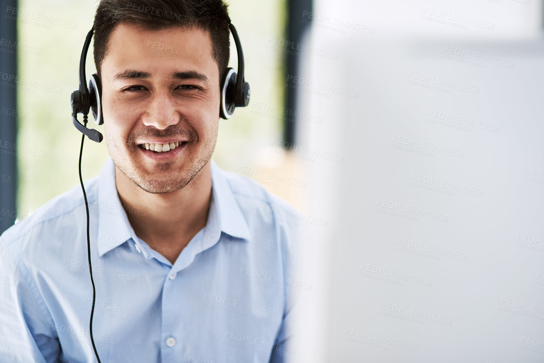 Buy stock photo Portrait of a happy young man wearing a headset and using a computer at work